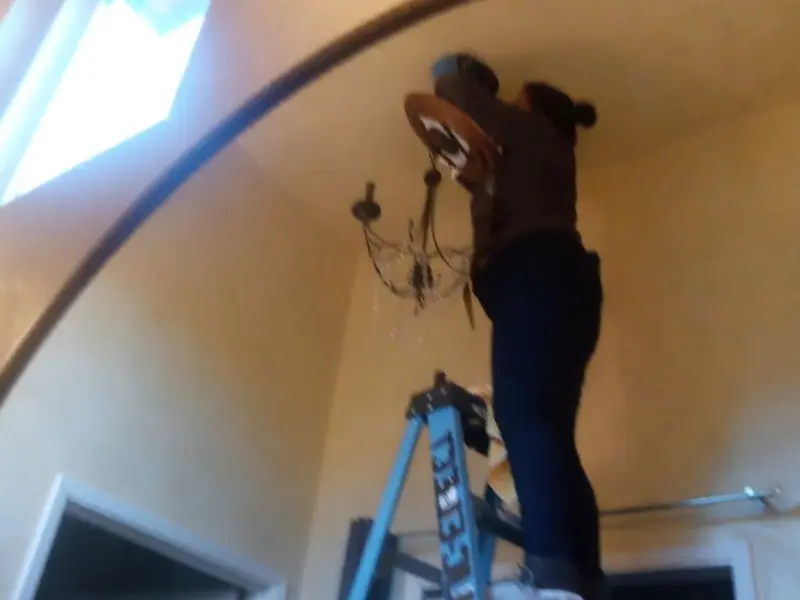 Electrician installing a chandelier in a Alton residence